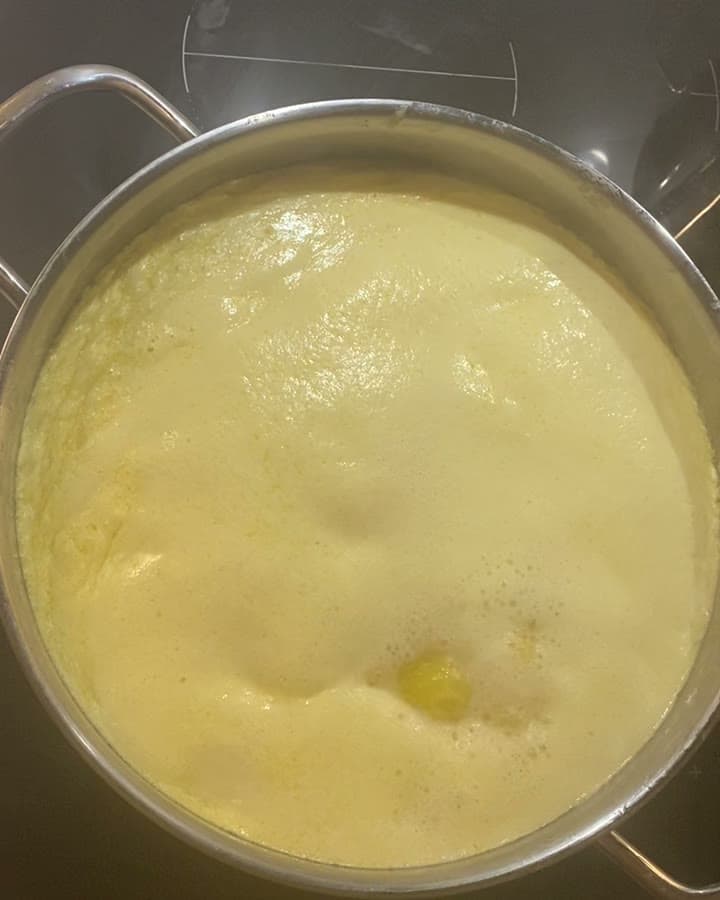 Milk foaming and rising in a pot on the stove