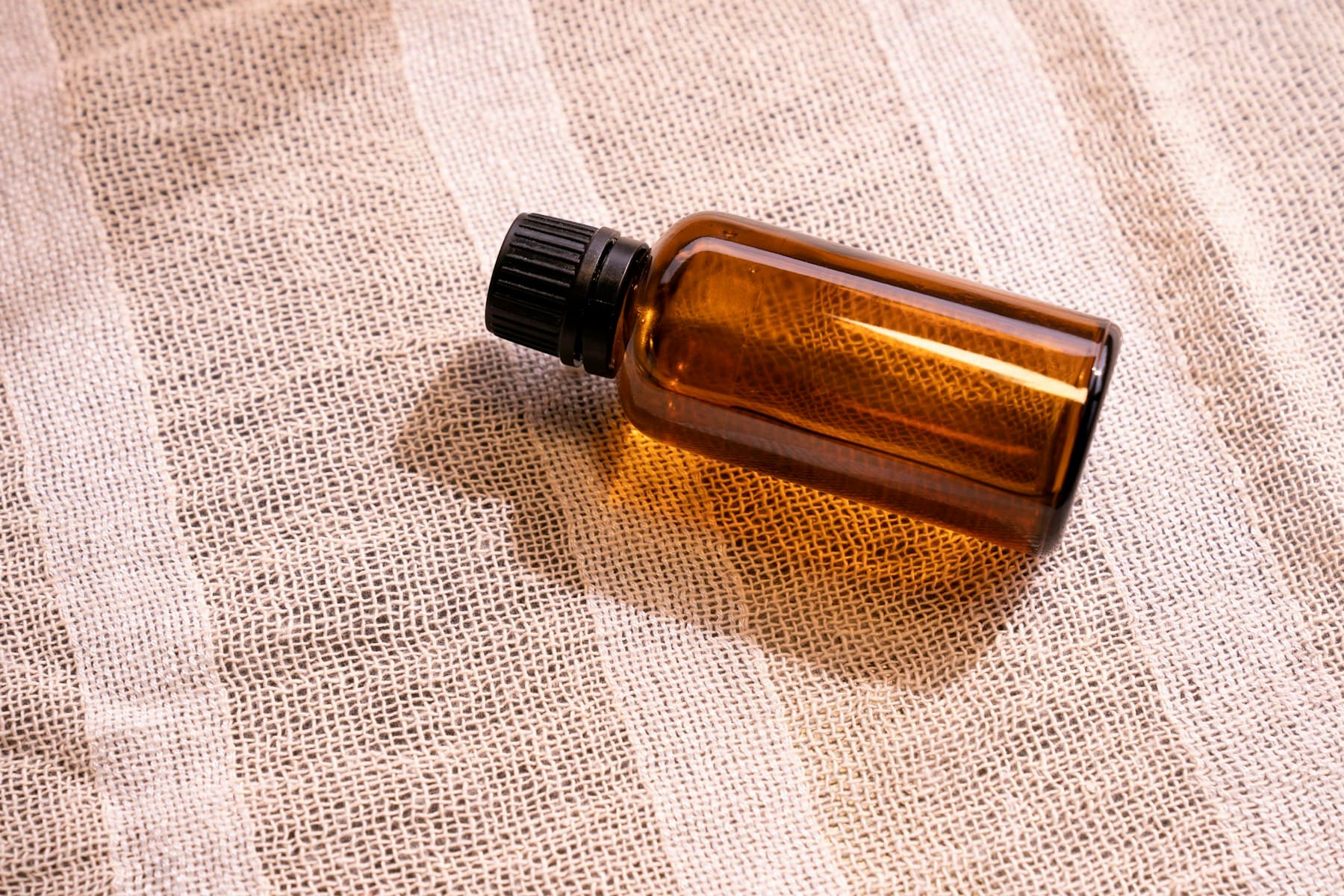 An amber oil bottle resting on soft fabric