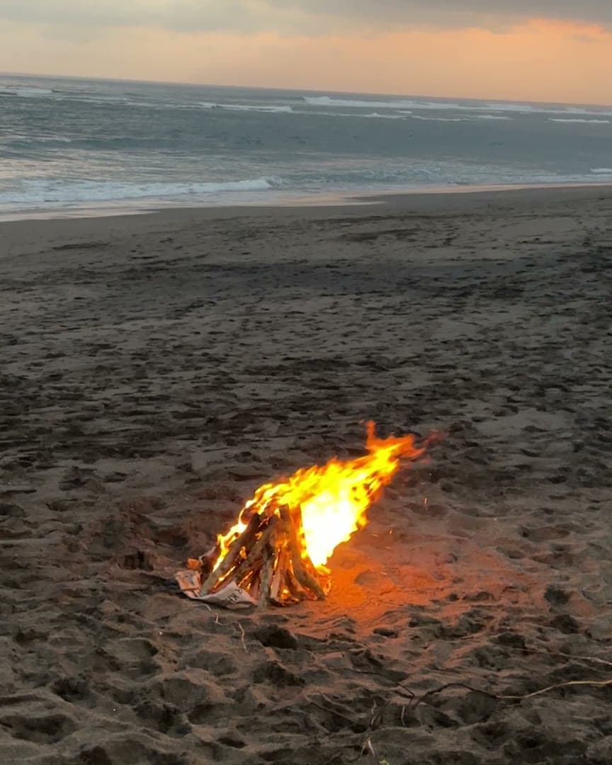 A small fire burning on the beach at dusk